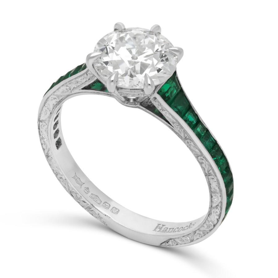 Round cut diamond with emerald shoulders